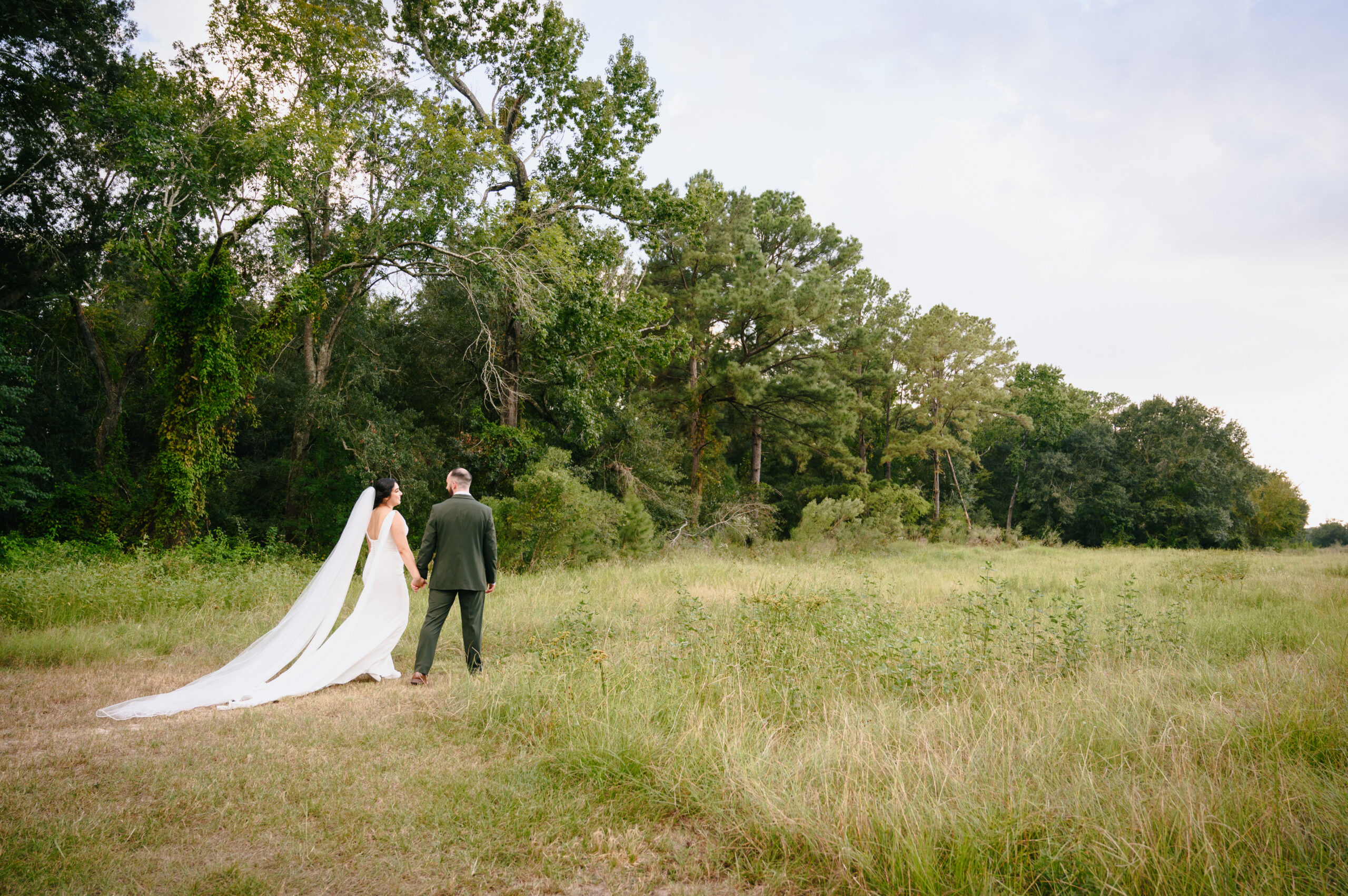 Bride and groom walking in open field, first look, cypress TX