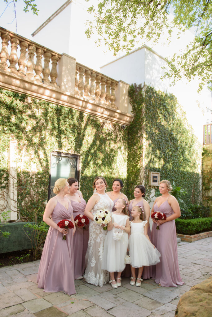 Bride and bridesmaids in front of stone wall, courtyard, bell tower on 34th 
