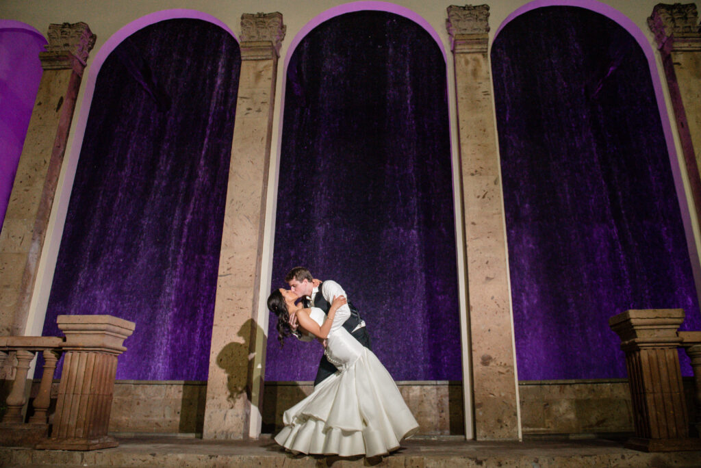 Bride and Groom kissing in front of waterfall wall, bell tower on 34th 